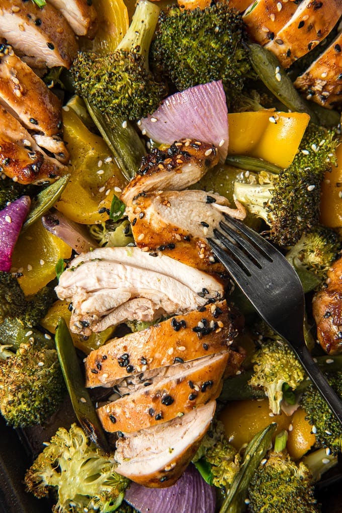 Sesame Chicken and vegetables on a sheet pan, chicken is sliced.