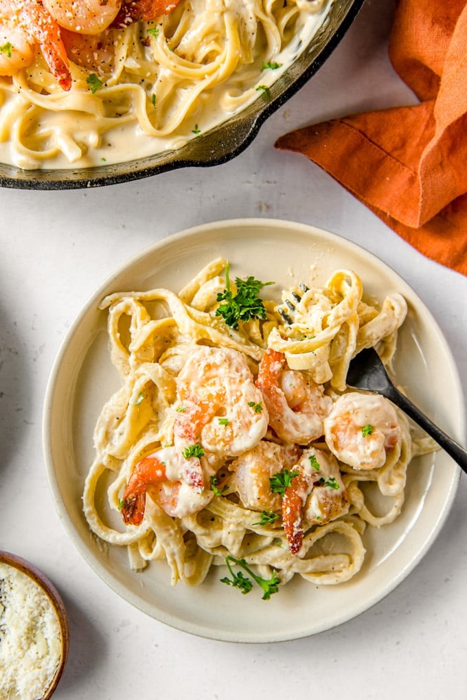 A plate with shrimp alfredo and a fork