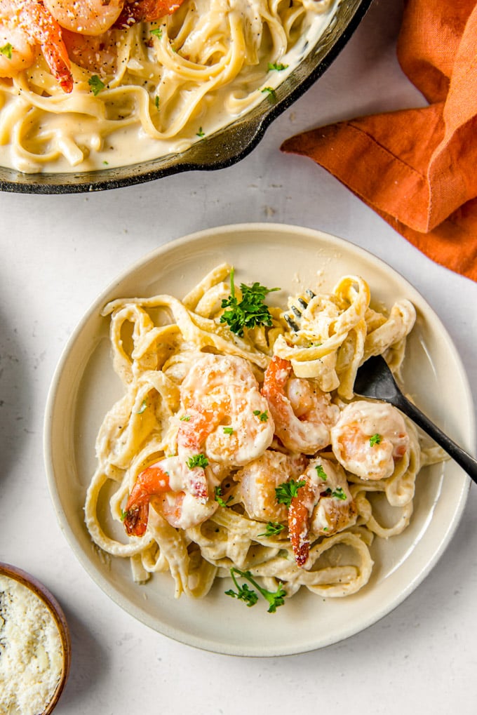 Shrimp Alfredo is a simple dinner for any night of the week, with a creamy homemade Parmesan cheese sauce topped with succulent, flavorful shrimp. A plate with shrimp alfredo and a fork
