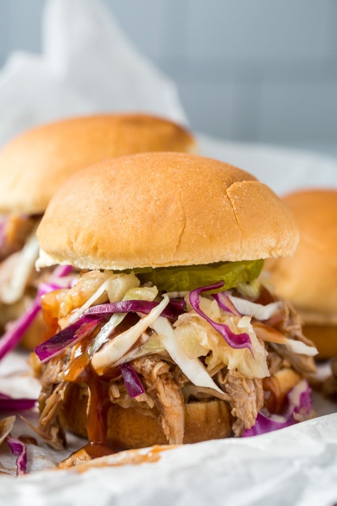 A close up image of a pulled pork slider with coleslaw and pickles