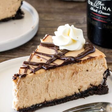 A slice of extra creamy Baileys cheesecake with an Oreo crust and chocolate ganache.