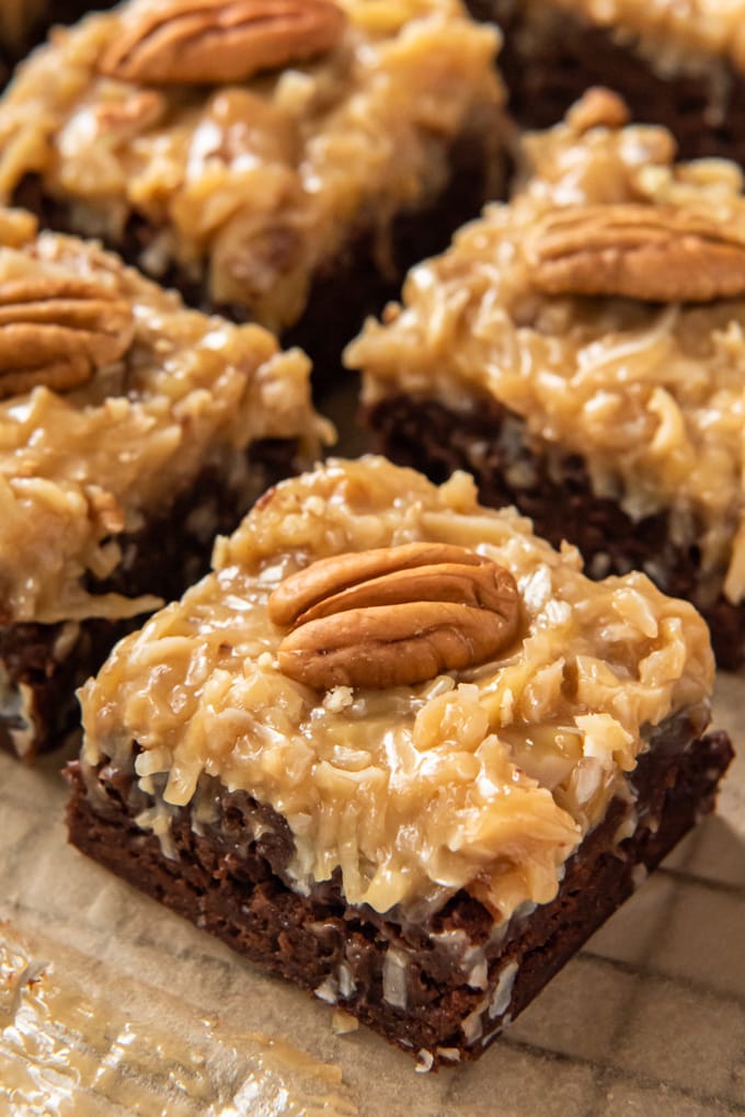 A close up image of a few brownies with coconut pecan frosting