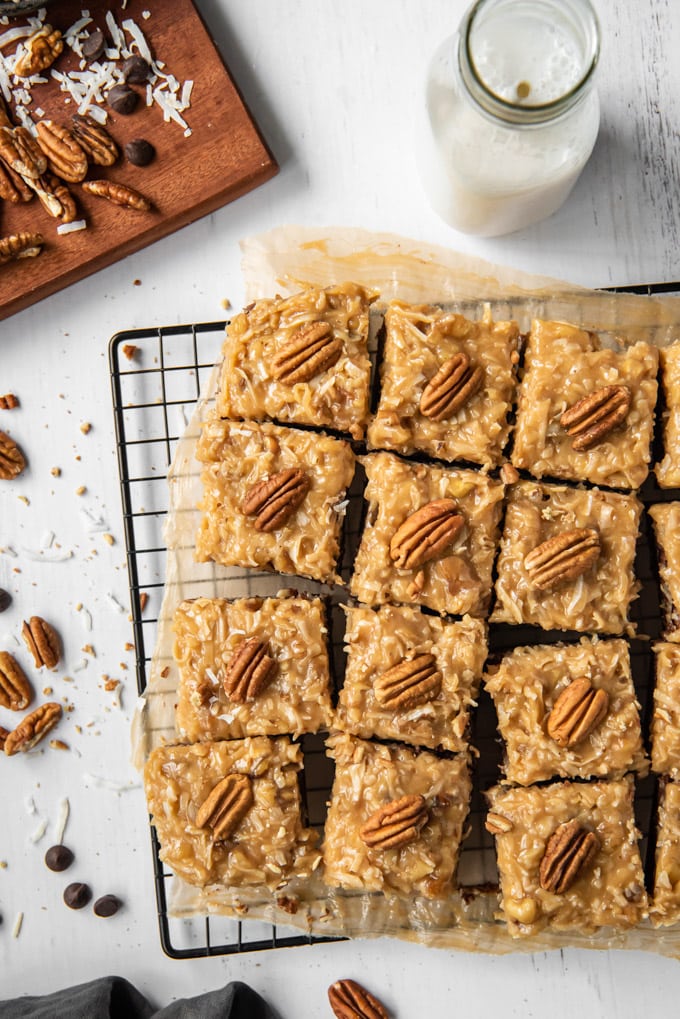 An overhead shot of a batch of brownies with german chocolate cake frosting, surrounded bu pecans and coconut