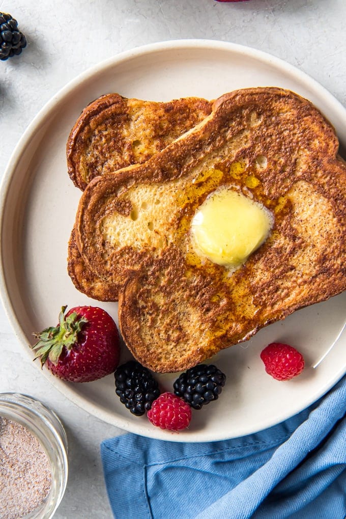 Two slices of french toast, stacked on a plate with fresh berries