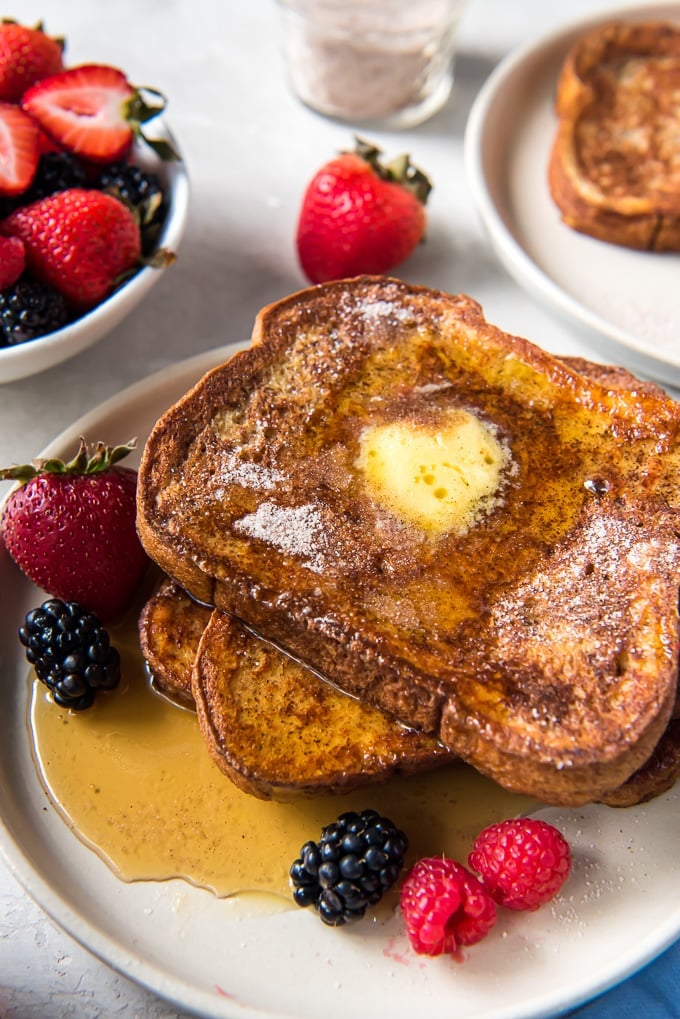 A plate with french toast, fresh berries and maple syrup.