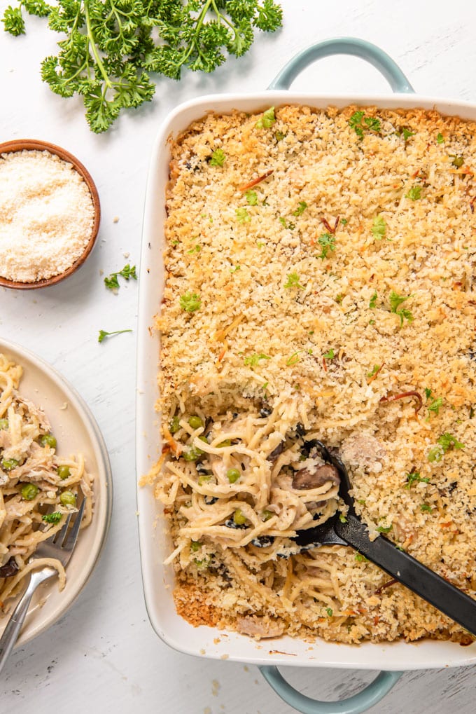 An overhead shot of a pan of turkey tetrazzini with a pasta spoon scooping some out.