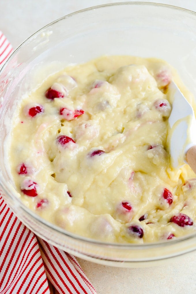 Cranberry Muffin batter in a glass bowl next to a red striped towel.