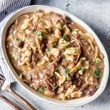 A dish filled with beef, gravy, and noodles.