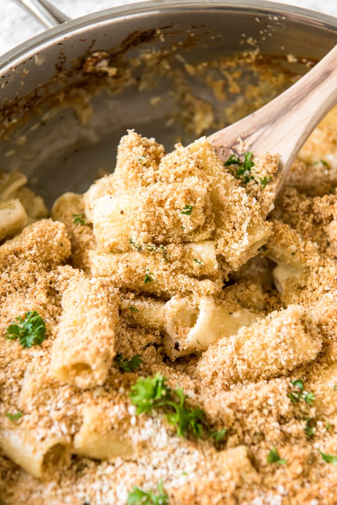 4 cheese rigatoni in a large skillet with a serving on a wood spoon