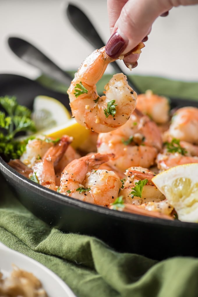 A plate of garlic shrimp with parsley and lemon