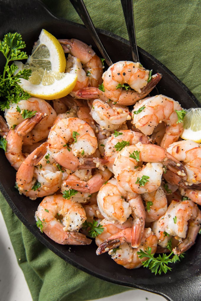 A plate of garlic shrimp with parsley and lemon