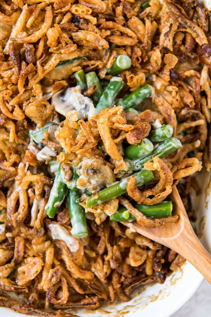 A scoop of green bean casserole on a wooden spoon