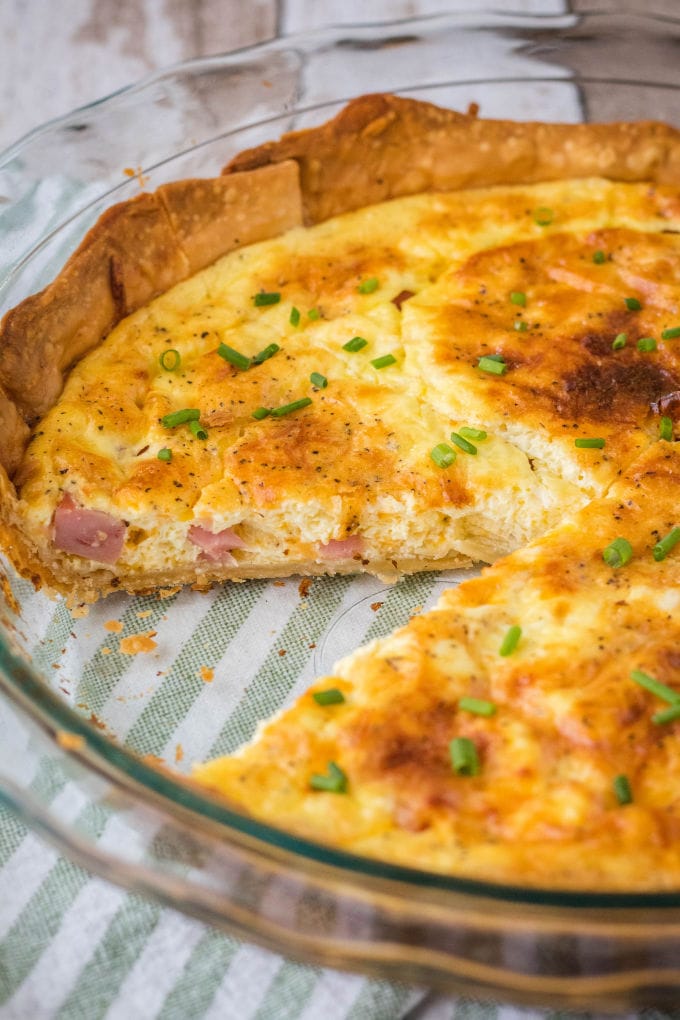 ham and cheese quiche in a pie plate with a slice removed