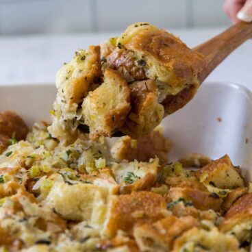 stuffing in a white baking dish with a serving on a wooden spoon