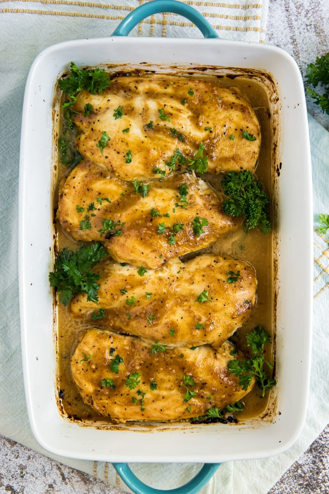 White baking dish, 4 chicken breasts with honey mustard sauce, parsley.