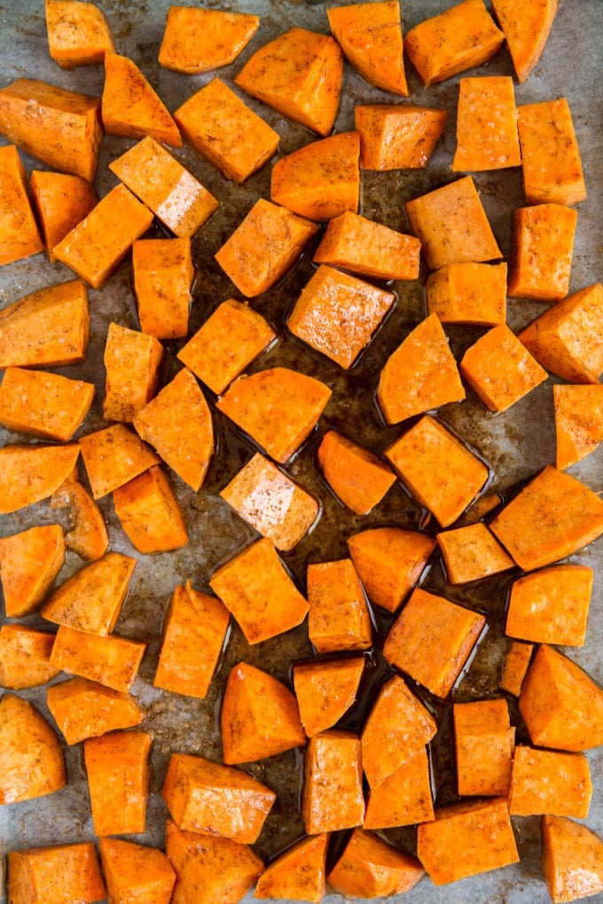 Cut up chunks of sweet potatoes on a sheet pan 