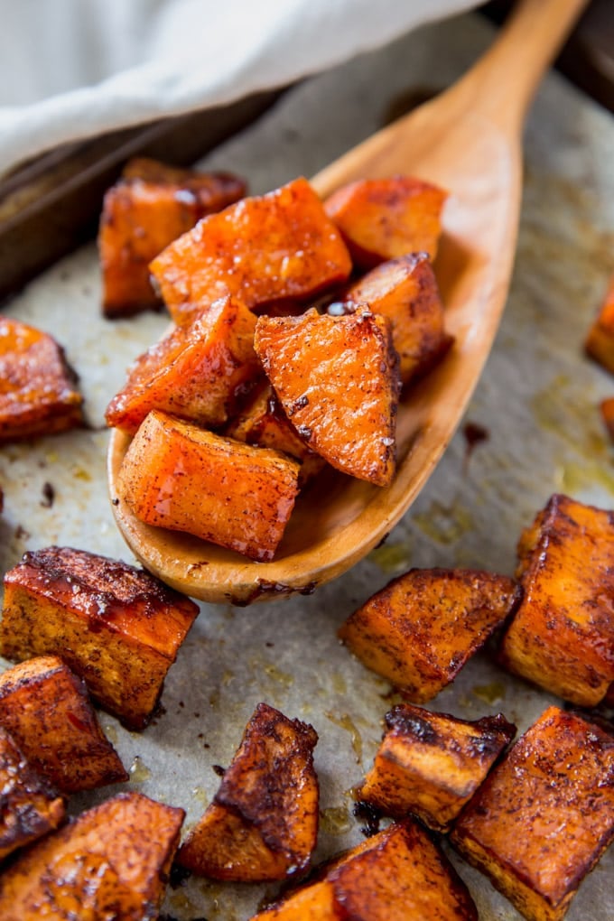 A close up of roasted sweet potatoes on a wooden spoon