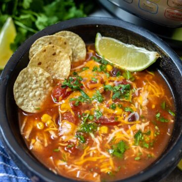 Bowl of Instant Pot Chicken Tortilla Soup topped with corn chips and fresh lime