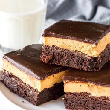 A plate of layered peanut butter brownies with a layer of peanut butter filling and chocolate on top.