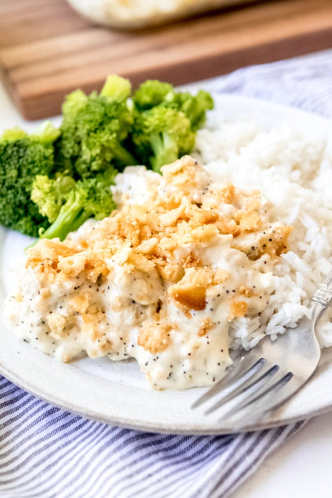 An image of poppy seed chicken casserole on a plate with broccoli and rice.