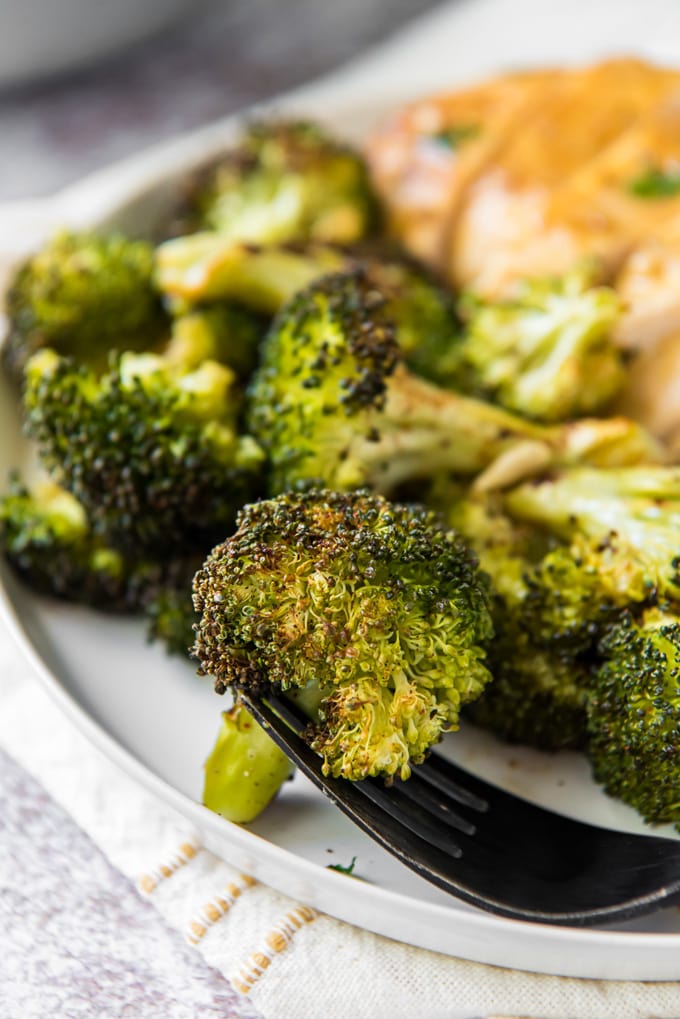a piece of roasted broccoli on a fork with more in the background.