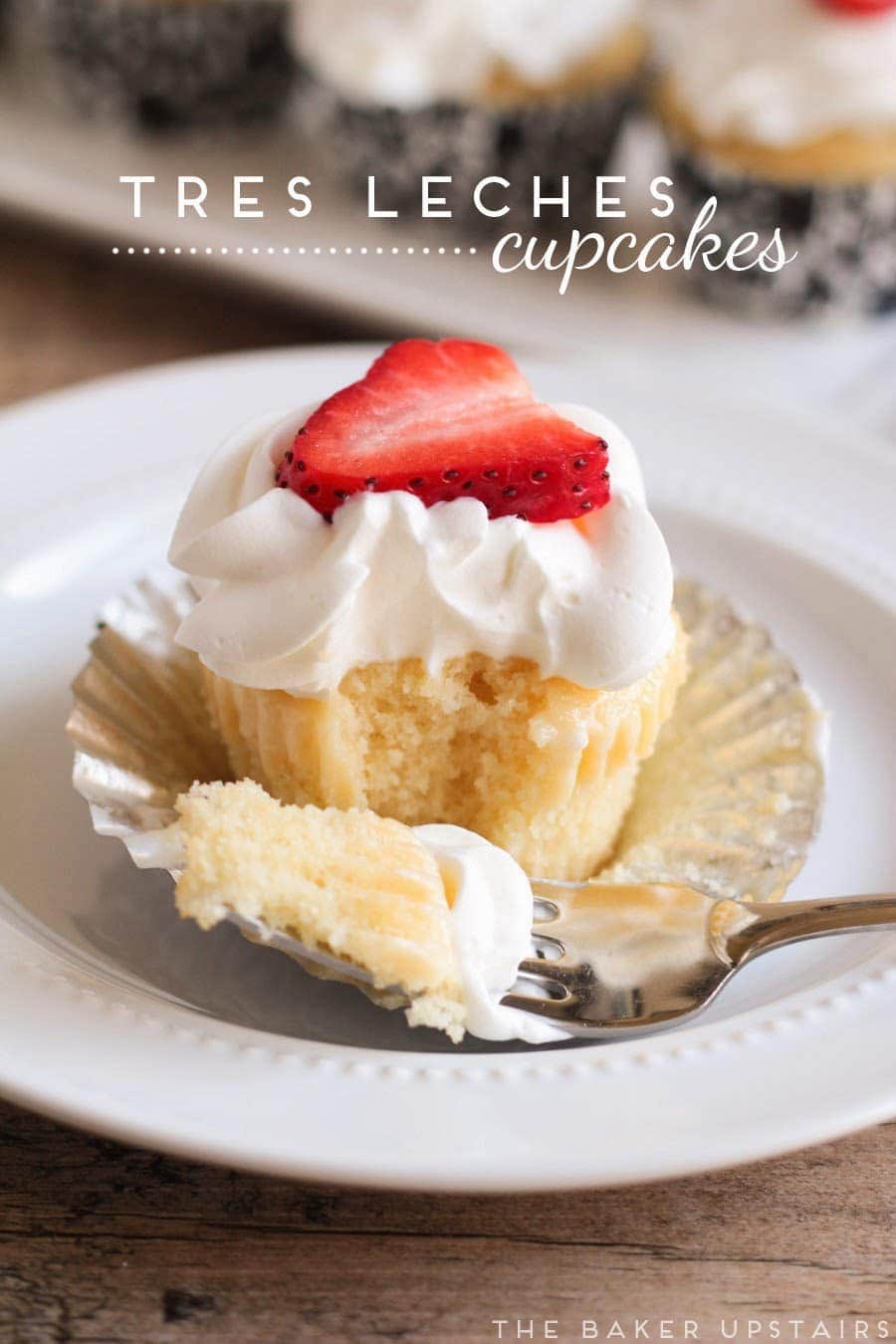 vanilla cupcake with white frosting, strawberry on top, a fork