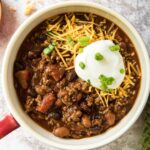 A bowl of chili with sour cream and cheese