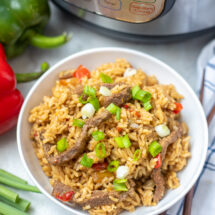 Instant Pot Pepper Steak in white bowl next to Instant Pot