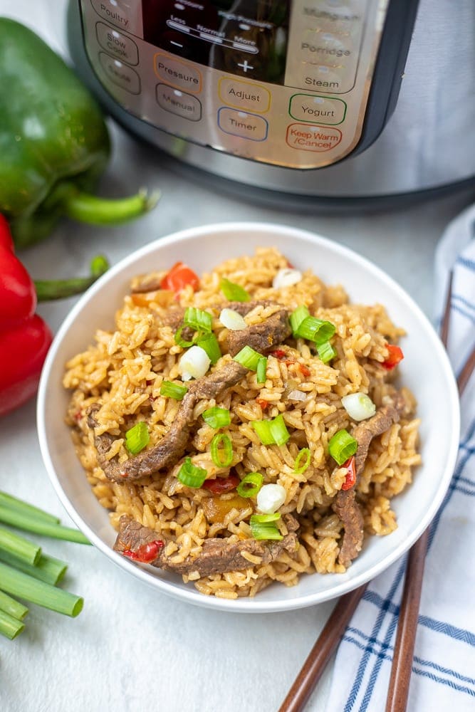 Instant Pot Pepper Steak in white bowl next to Instant Pot