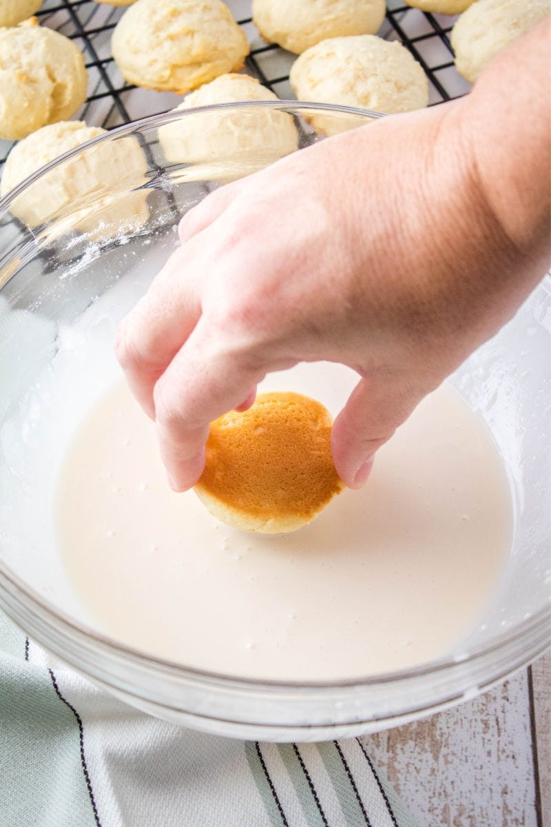 Italian Ricotta Cookies are a fluffy treat that begs to be eaten! Top them with your favorite seasonal sprinkles for an irresistible cookie perfect for the holidays! top of a ricotta cookie being dipped into vanilla glaze