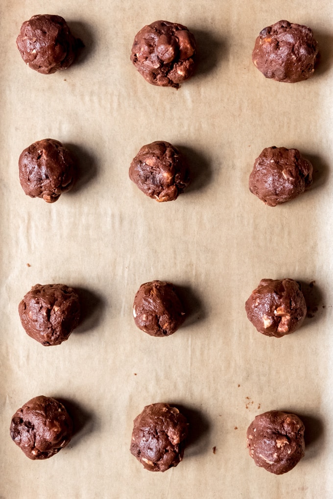 An image of balls of chocolate cookie dough on a baking sheet.