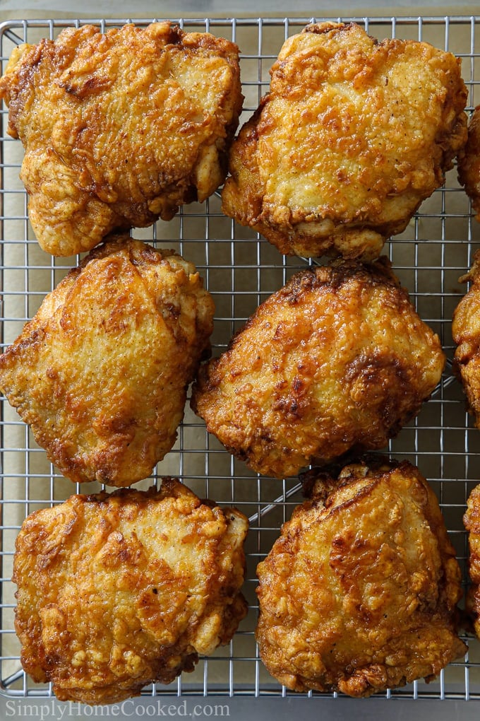 an overhead image of crispy fried chicken thighs cooling on a wire rack