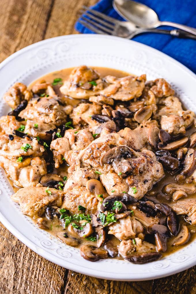 Plated Instant Pot chicken thighs on wood table.