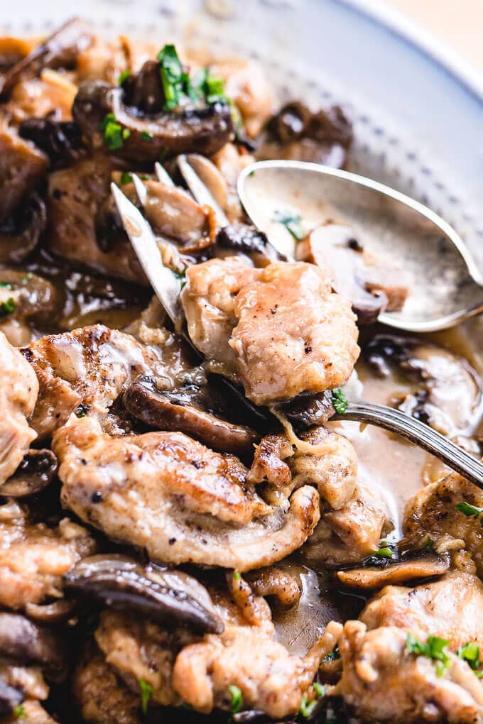 Plate of Instant Pot chicken thighs with close up of fork holding a piece of chicken.