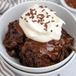 Chocolate Pudding Cake in a white bowl topped with whipped cream and chocolate sprinkles.