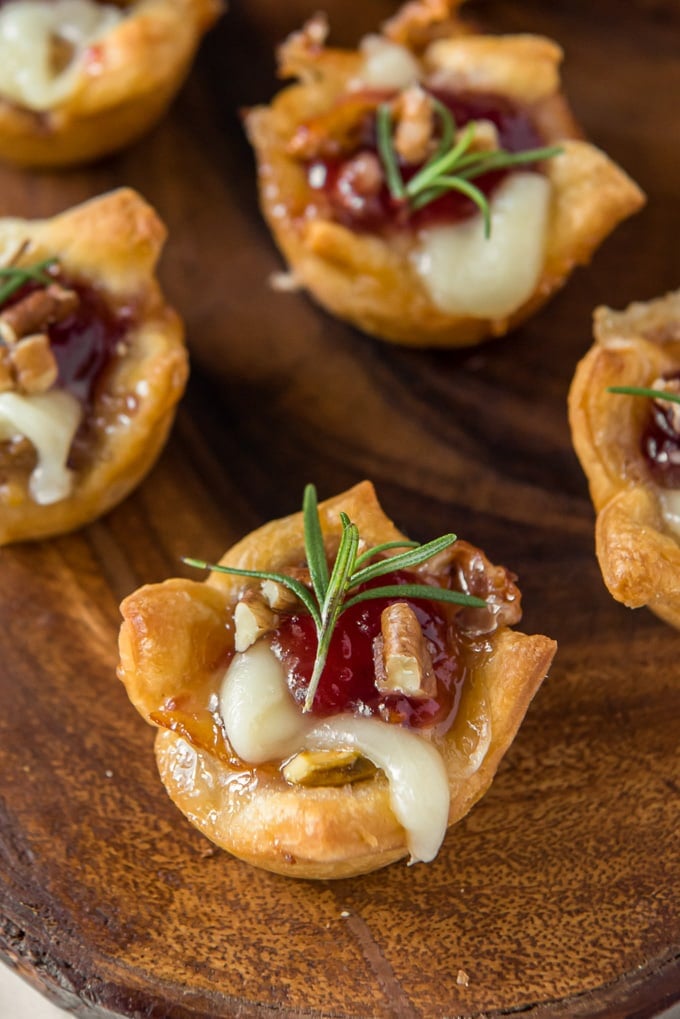 Cranberry brie bites on a wooden surface.