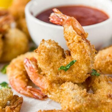 A close up of fried shrimp with dish of cocktail sauce