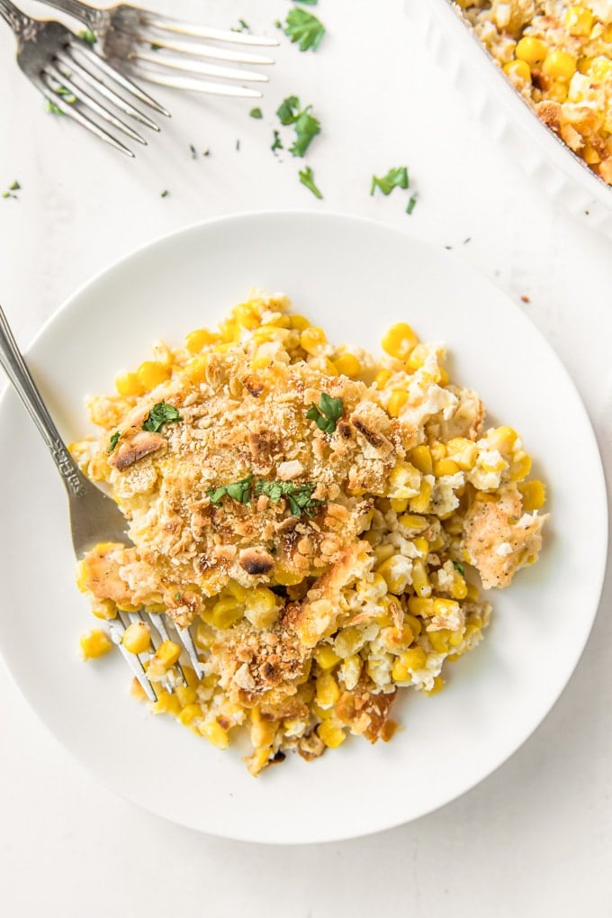 A small plate with a serving of scalloped corn casserole and a fork