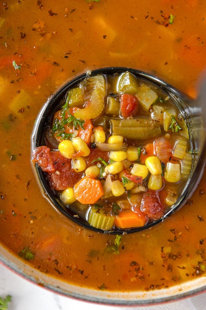 Vegetable soup in a ladle over broth.