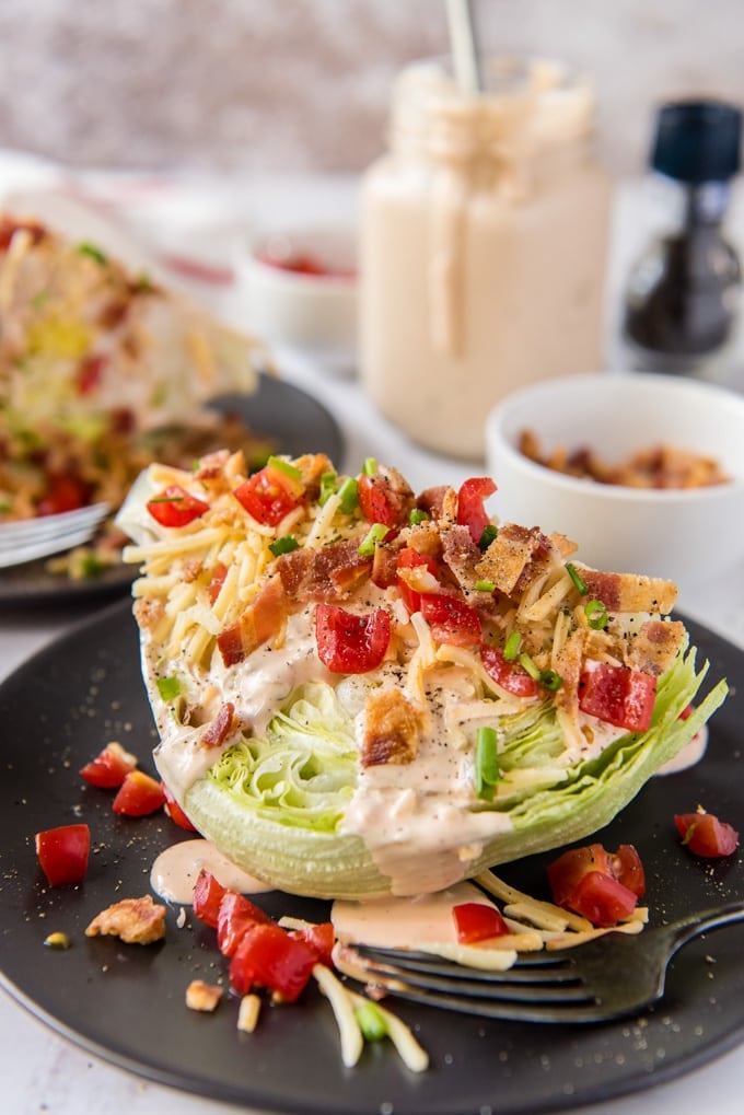A classic wedge salad with bacon, tomatoes, shredded cheese and thousand island dressing.