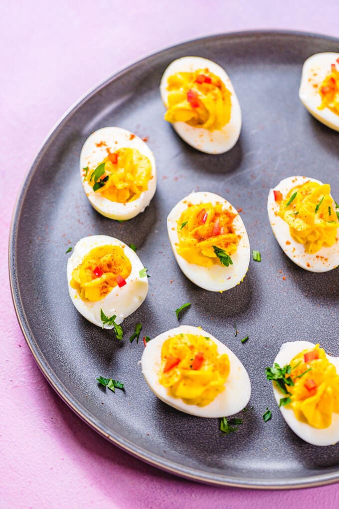 Deviled eggs in grey plate on pink background.