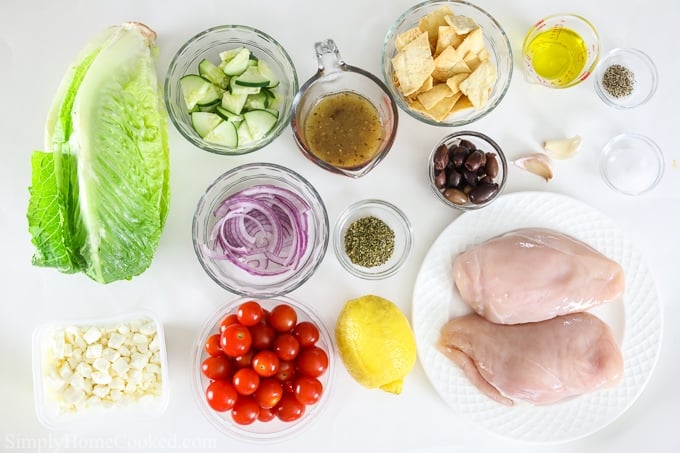 An overhead image of greek chicken salad ingredients on a plain white background