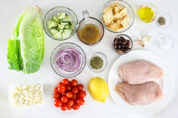 Ingredients for a recipe prepped, chopped and in small bowls - Lettuce, feta cheese, chicken, lemons, onions, tomatoes, cucumbers and seasonings.