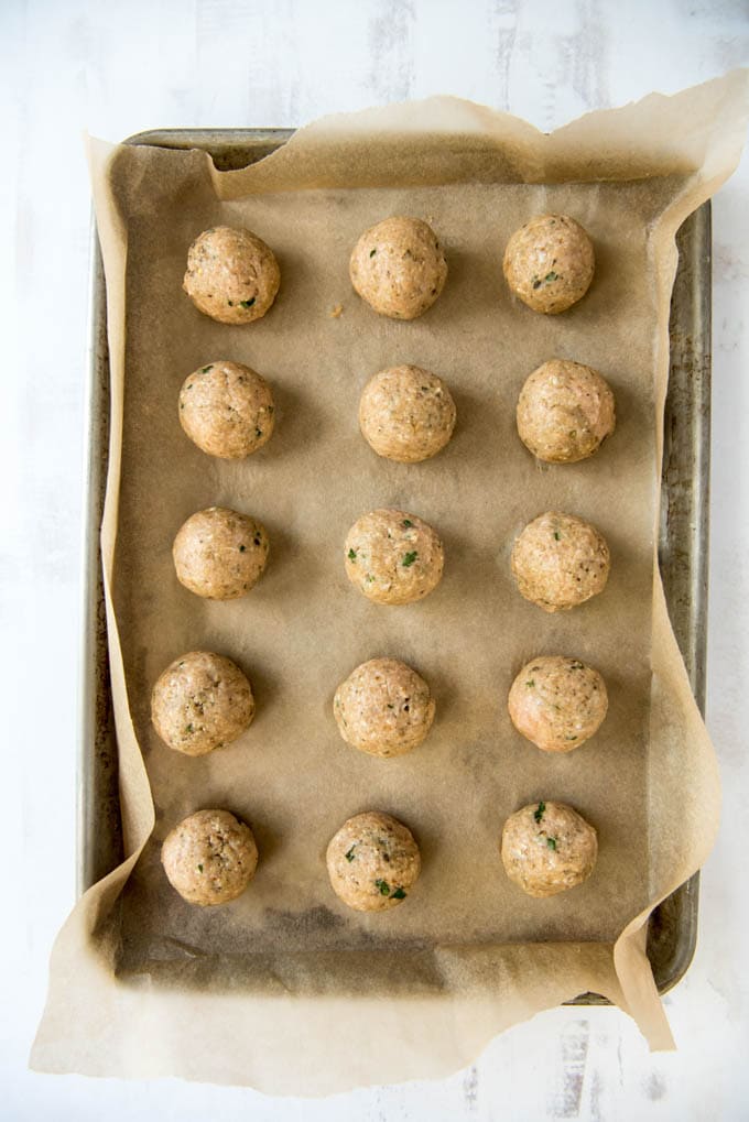 uncooked chicken meatballs on a sheet pan