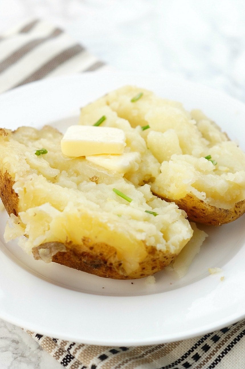 An instant pot baked potatoes split, with butter and chives