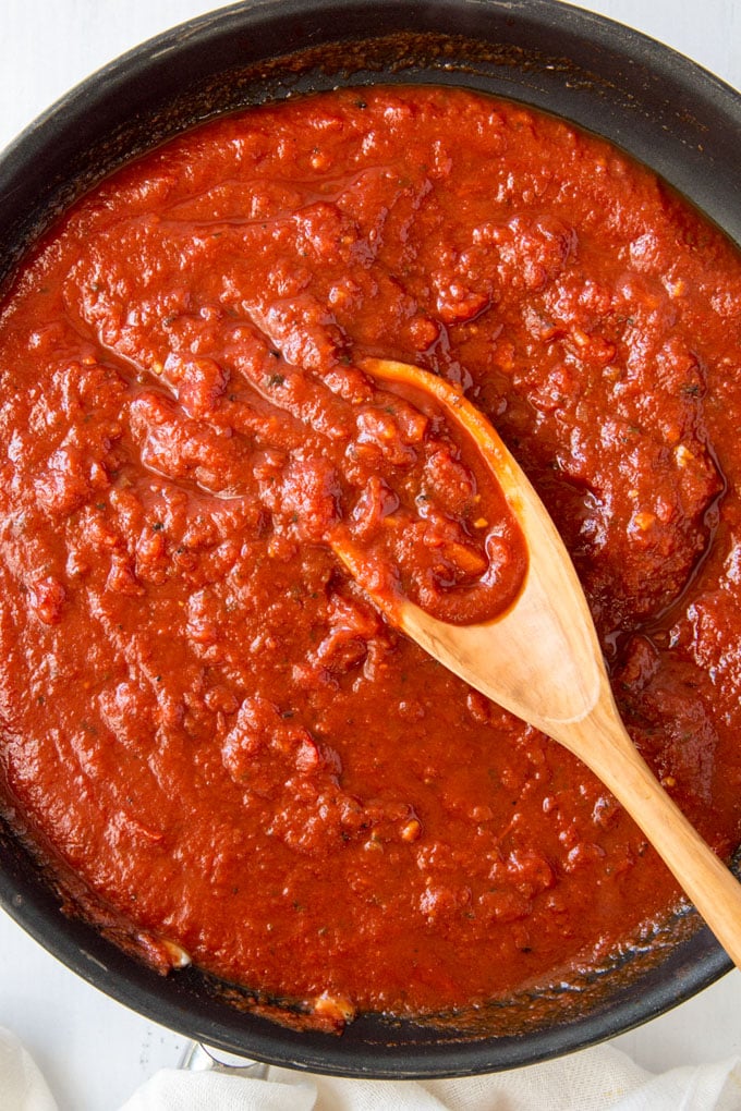 a pan of marinara sauce in a skillet with a wooden spoon