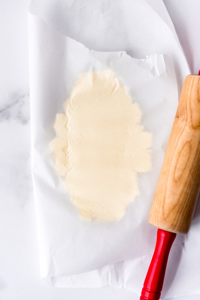 An image of a stick of butter that has been pounded between parchment paper with a rolling pin.