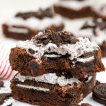 Two Oreo Brownies stacked on top of each other on a piece of parchment paper.