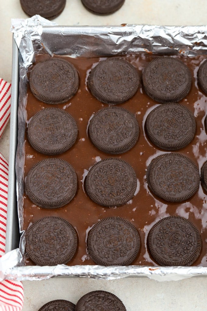 Brownie batter in a metal pan topped with Oreos.