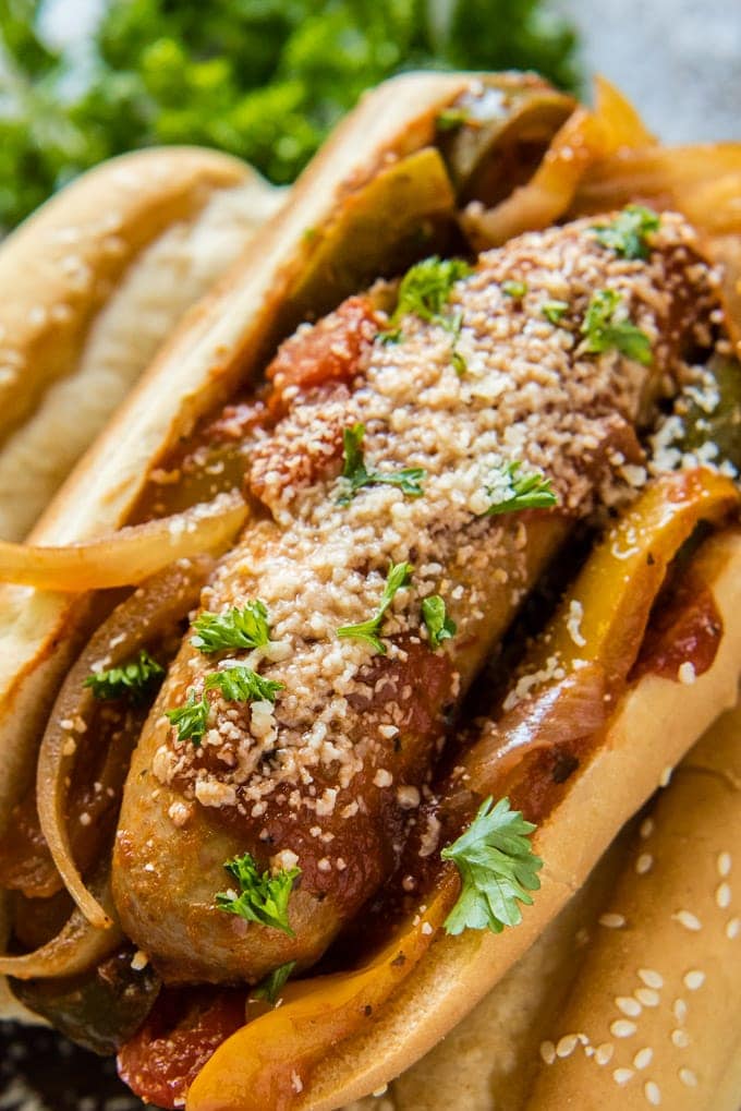 A close up overhead image of italian sausage in a hoagie roll with onions and peppers.